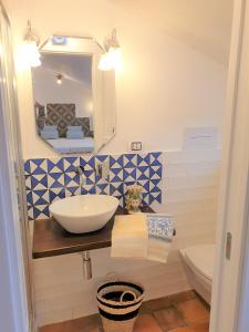 un bagno con lavandino, water e specchio di MARATEA SUNSET SUITE a Maratea
