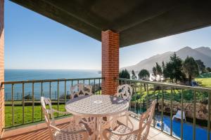 una mesa y sillas en un balcón con vistas al océano en Villa La Ballena de Sonabia, en Oriñón