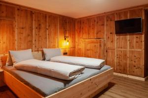 two beds in a room with wooden walls at Schneggnheisl Panoramaappartements in Sautens