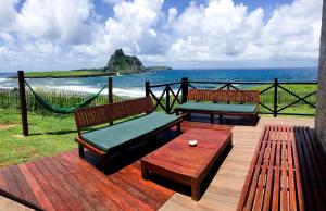 Dois bancos e uma rede de descanso num deque com vista para o oceano em Casa dos Tubarões em Fernando de Noronha