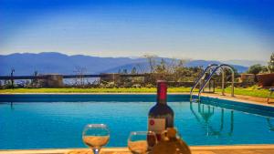 a bottle of wine and two glasses next to a swimming pool at villa fairytale in Nerotriviá