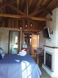 sypialnia z niebieskim łóżkiem i kominkiem w obiekcie Chalé Safira w mieście Monte Verde
