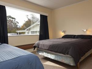 a bedroom with a bed and a large window at Kune Crib - Ohakune Holiday Home near Turoa in Ohakune