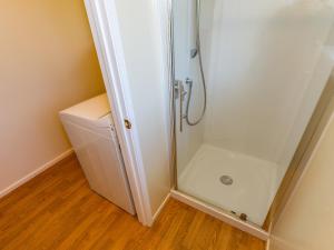 a shower with a glass door next to a washer at Kune Crib - Ohakune Holiday Home near Turoa in Ohakune +22 photos