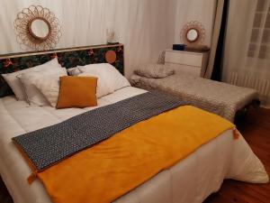 a bedroom with a large bed with an orange blanket at La maison d'à côté in May-sur-Orne