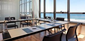 a restaurant with long tables and chairs and windows at Hotel Príncipe de Asturias in Gijón