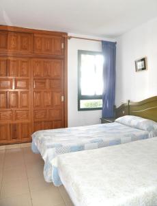two beds in a bedroom with wooden cabinets and a window at Sunny Silencio Park in Arona