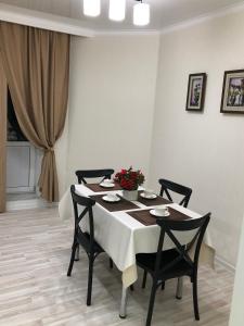 a dining room table with four chairs and flowers on it at Apartment Батыс 2, 44 in Aktobe