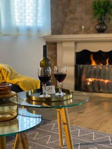 two glasses of wine on a table in a living room with a fireplace at Isabel House Alojamento Rural in Pampilhosa da Serra