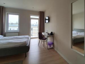 a hotel room with a bed and a desk and a window at Chopin Apartments - Eco in Warsaw