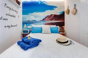 a white bed with a hat and blue pillows on it at Marlin II Puerto del Carmen in Puerto del Carmen +27 photos