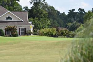 een golfbaan met een huis en een green bij Pool View Villa 1504 with Golf Course in Calabash