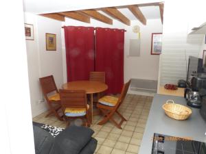 a kitchen with a table and chairs and a red curtain at Gênois 1 in Hourtin