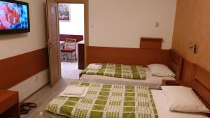 a hotel room with two beds and a television at Guest House Boska in Pančevo