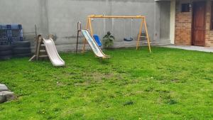 un patio con un parque infantil con columpios en Villa Victoria, en Machachi