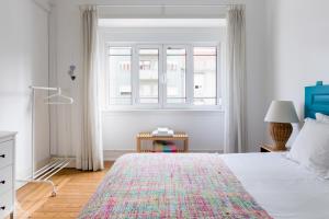 a white bedroom with a bed and a window at Casa da Avenida Lisboa in Lisbon