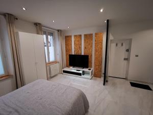 a bedroom with a bed and a flat screen tv at Studio entre Paris et Versailles in Le Port-Marly