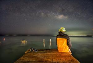 a man sitting on a dock looking at the night sky at Amigos Hotelito in Bacalar