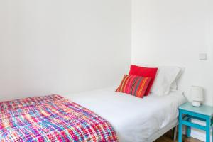 a white bed with a red pillow and a blue table at Casa da Avenida Lisboa in Lisbon