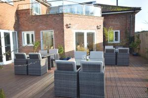 a patio with wicker chairs and a table on a deck at Lakeside Old Hunstanton in Hunstanton