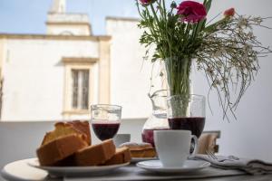 a table with bread and a vase of flowers and two glasses of wine at Carlo Alberto Room in Fasano
