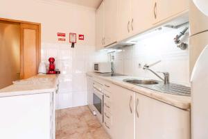 a kitchen with white cabinets and a sink at Marble House in Póvoa de Varzim