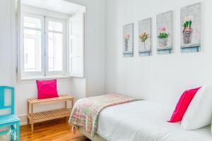 a white bedroom with a bed and two windows at Casa da Avenida Lisboa in Lisbon