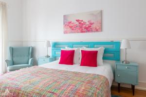 a bedroom with a bed and two blue chairs at Casa da Avenida Lisboa in Lisbon