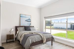 een slaapkamer met een bed en een groot raam bij Luxury Apartments and Motel Rooms - Free Wifi - Close To Beach in Carpenter Rocks