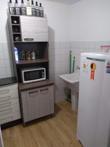 a kitchen with a microwave on a counter with a refrigerator at Minha casa é sua casa in Curitiba