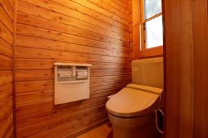 een badkamer met een toilet in een houten muur bij Aiwa no Mori Hotel in Ina