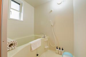 een witte badkamer met een bad en een douche bij Aiwa no Mori Hotel in Ina