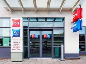 a building with glass doors and signs in front of it at ibis Birmingham International Airport – NEC in Bickenhill