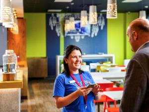 a woman standing in a restaurant holding a cell phone at ibis budget London Hounslow in Hounslow