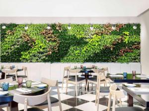 a restaurant with tables and chairs and a green wall at Ibis Deira City Centre in Dubai