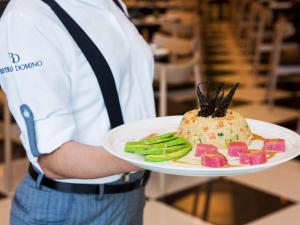 a man holding a plate with a cake and vegetables at ibis Deira Creekside Dubai in Dubai