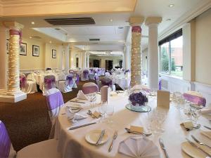 a banquet hall with white tables and purple chairs at Mercure Winchester Wessex Hotel in Winchester