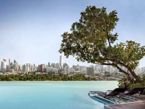 a pool with chairs and a tree and a city at SO/ Bangkok in Bangkok
