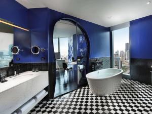 a bathroom with a tub and a blue wall at SO/ Bangkok in Bangkok