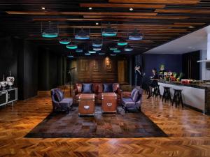 a woman standing in a lobby with chairs and a bar at SO/ Bangkok in Bangkok
