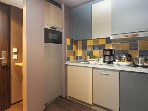 a kitchen with white cabinets and tiles on the wall at Aparthotel Adagio Köln City in Cologne