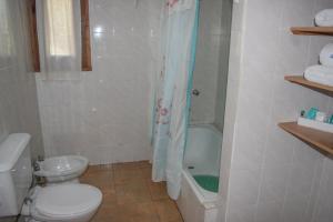 La salle de bains blanche est pourvue d'une douche et de toilettes. dans l'établissement Cabañas Rucaleufu, à San Martín de los Andes