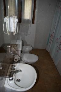La salle de bains est pourvue d'un lavabo blanc et de toilettes. dans l'établissement Cabañas Rucaleufu, à San Martín de los Andes