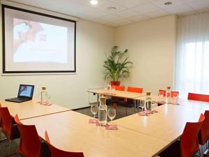 a meeting room with tables and chairs and a projector screen at Ibis Kaunas Centre in Kaunas