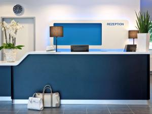 a reception desk in an office with a blue wall at Ibis Budget Montbéliard in Montbéliard