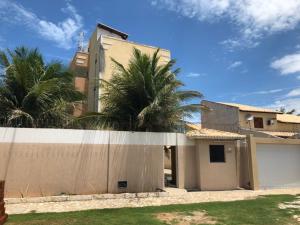 a house with palm trees behind a fence at Apartamento Beira Mar no 2ºAndar - TIBAU DO NORTE - RN in Tibau do Sul