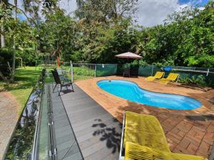 a swimming pool with yellow chairs next to a fence at Beerwah Motor Lodge in Beerwah