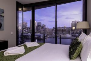 a bedroom with a large window with a view of the city at AKOM AT Docklands in Melbourne
