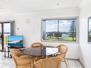 a dining room with a table and chairs and windows at Oxley 8 at Tuncurry in Tuncurry