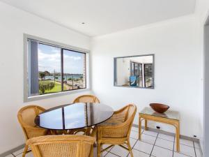 a dining room with a table and chairs and two windows at Oxley 8 at Tuncurry in Tuncurry